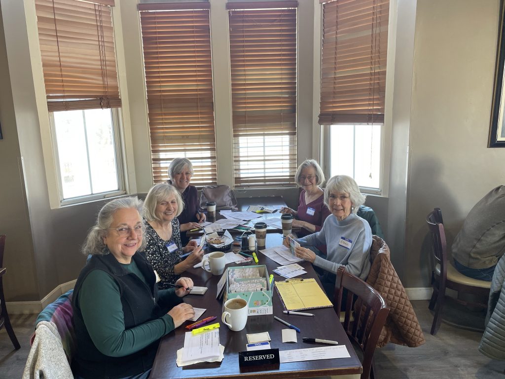 A group sits at a table writing postcards